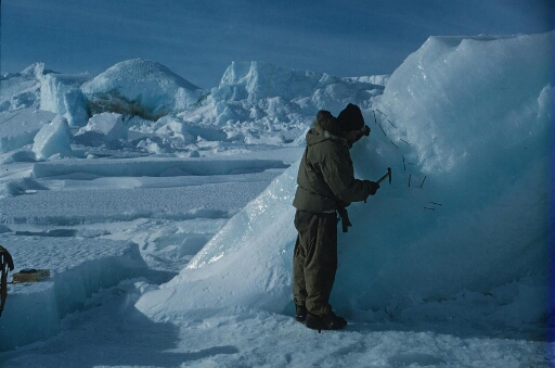 Dans la zone chaotique du glacier de l'Astrolabe, un glaciologue examine et prélève des échantillons de glace.