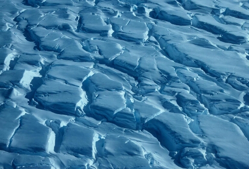 Survol à basse altitude du glacier de l'Astrolabe ou de l'un de ses icebergs. Gros plan sur sa surface crevassée.