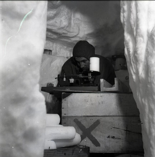 Dans le labo creusé dans la glace, Claude Lorius pèse une carotte de glace prélevée dans le névé.
