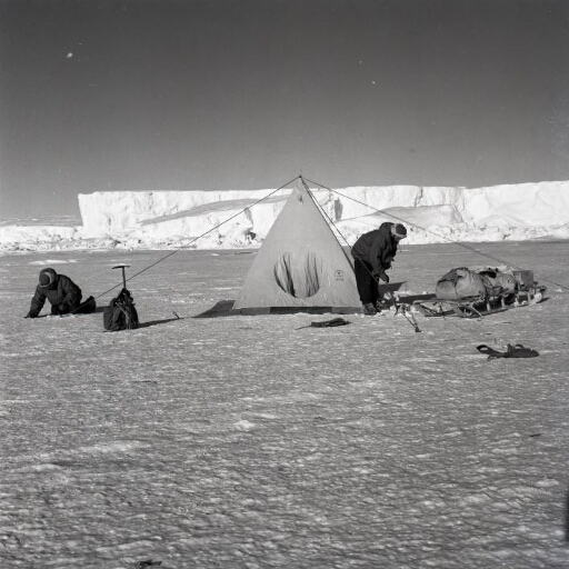 Deux hivernants devant une tente installée sur la banquise. A l'arrière-plan, le glacier de l'Astrolabe.