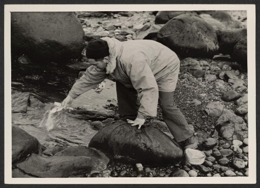 Un homme lave ses couverts de repas dans un ruisseau
