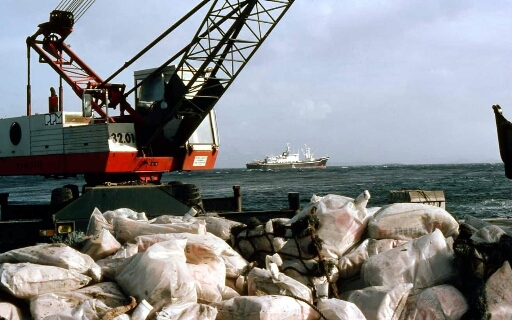 À Port aux Français (PAF), quai du port encombré de sacs de ciment au loin le Marion Dufresne I au mouillage