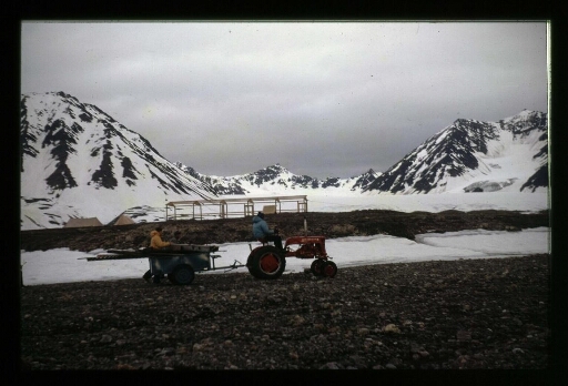 Construction de la base Corbel; un homme sur un tracteur tracte une remorque ou s'y trouve un homme - mission CNRS 1965 -vue 2