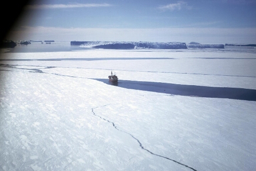 Vue prise d'hélico du Thala Dan progressant dans la banquise. Au-delà d'une ligne d'icebergs, mer libre.