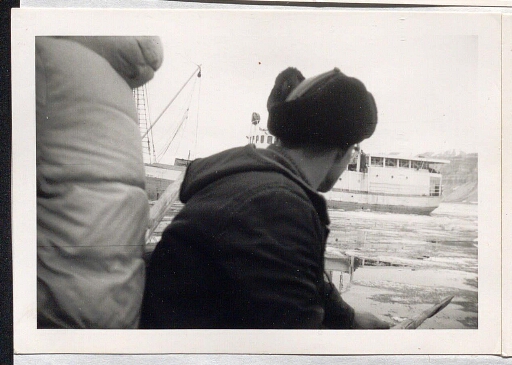 un homme de dos qui observe un navire qui passe près de lui, entre des morceaux de glace
