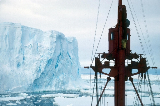 Vue prise de la passerelle du Thala Dan naviguant dans le pack très près d'un gros iceberg tabulaire.