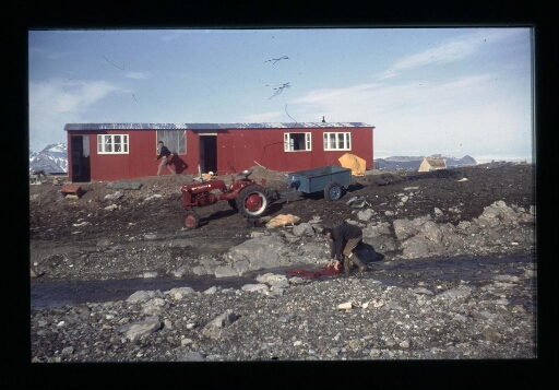 Un homme près d'un tracteur devant l'atelier de la base Corbel - mission CNRS 1966