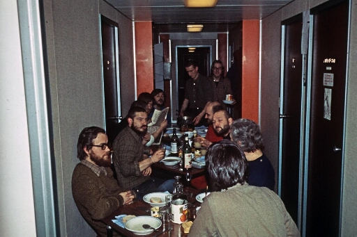 Le bâtiment séjour ravagé par un incendie le 23.07.1973 : la salle à manger improvisée dans le couloir du batiment dortoir. Les hivernants à table.