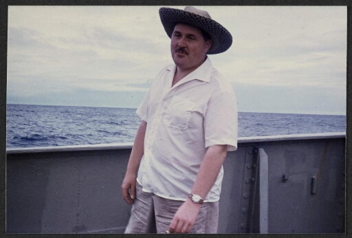 Un homme à chapeau et en chemise sur le pont d'un bateau