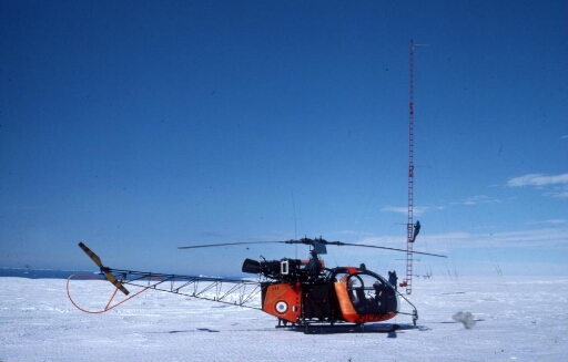 Programme IAGO pour l'étude des vents catabatiques. Sur le continent, à D 10, montage du pylône aérologique, pose des haubans. L'hélicoptère Alouette 2.