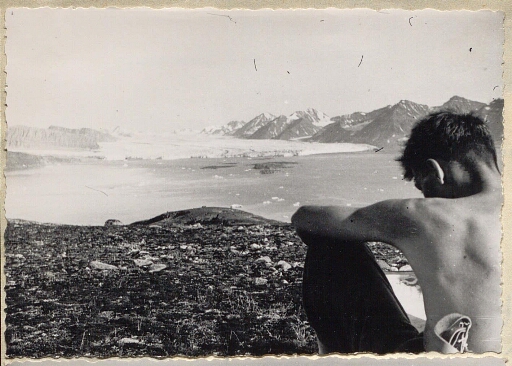 Un homme assis, torse-nu avec une vue sur un glacier et les sommets des Tre Kronor