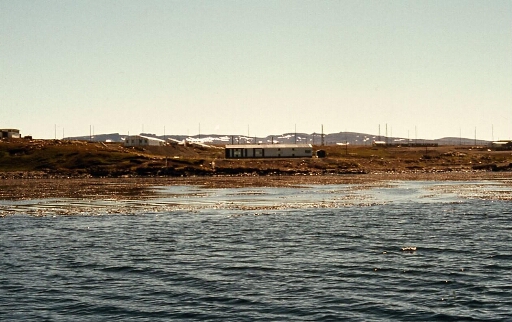 La base de Port aux Français vue de la mer (PAF) avec  le laboratoire de Biologie Marine (Biomar) sur la gauche un bout de la Chapelle et l'alignement des Fillods B au fond les antennes