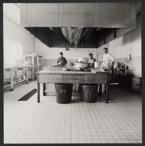 Trois cuisiniers derrière le plan de travail central de la cuisine.