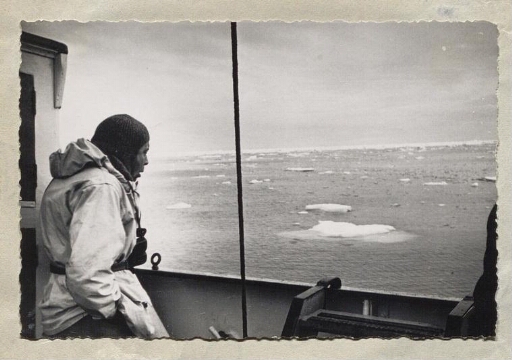 Un homme sur le pont du navire Lyngen qui regarde la mer ou flotte ou des morceaux de glace