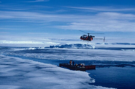 A l'ouest de l'île, l'hélicoptère Alouette 2 survole un ponton de débarquement pour une opération de transport. Sept hommes sur le ponton