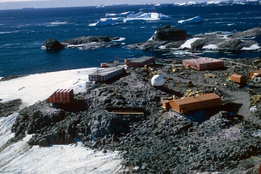 Survol, vers le nord-est, du centre de la base et de l'île du Lion. Mer libre et icebergs à perte de vue. Très beau temps calme.