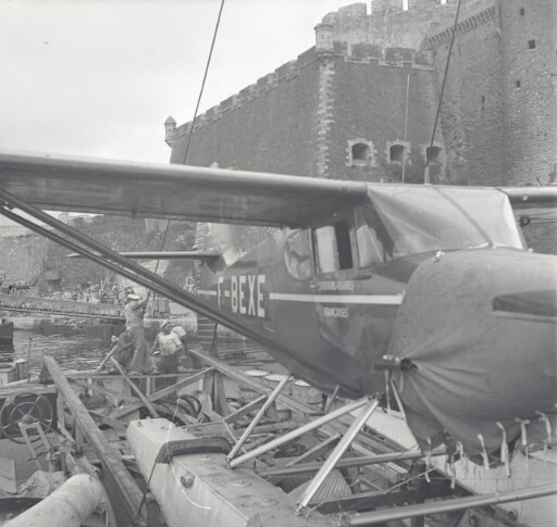 L'hydravion arrimé en poupe du navire en rade de Brest, sous la citadelle Vauban. Trois matelots de la Marine nationale.
