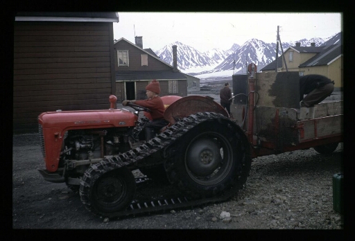 Dans un village de Ny-Ålesund, un enfant au volant d'un tracteur à chenilles qui tracte une remorque- mission CNRS 1964 - vue 1