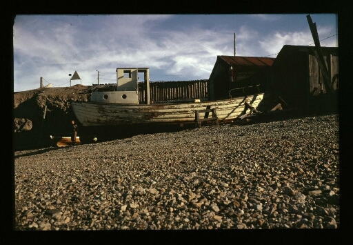 Petit bateau en bois sur la grève dans le port de Ny-Ålesund- mission CNRS 1963