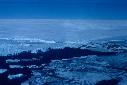 Vue aérienne vers le sud-ouest en direction de l'archipel, du glacier de l'Astrolabe et du continent. Alternance de pack et de mer libre. Les icebergs issus du glacier.
