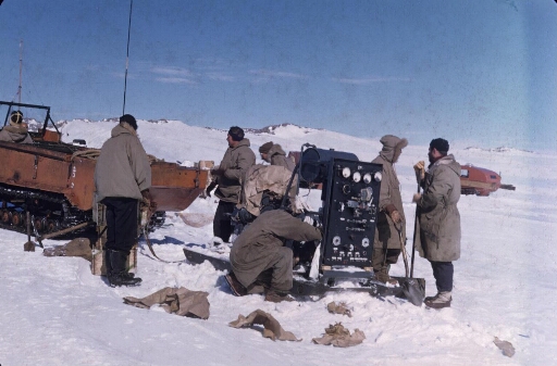 Le groupe électrogène déballé est prêt pour remorqué jusqu'à la base. Sept hommes préparent l'opération. Deux weasels.