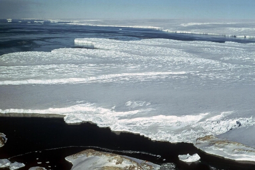 Survol du glacier de l'Astrolabe. Au premier plan l'île Jean Rostand et le nunatak du Bon Docteur. A l'arrière-plan, le continent.