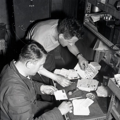 Deux hommes dont le radio-gérant postal René Merle (premier plan) préparent le courrier.
