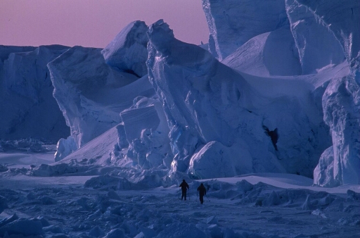 Au cours de l'hiver la banquise permet l'exploration du chaos aux abords du glacier de l'Astrolabe à ces deux hivernants. Belle lumière très bleue, ciel mauve.