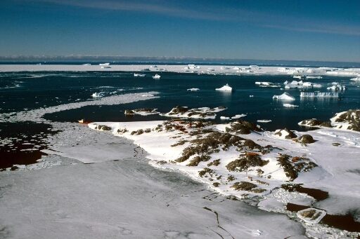 Vue aérienne de l'île des Pétrels en direction des îles Cuvier et du Lion. Alternance de banquise, pack et mer libre. Le Thala Dan amarré à la pointe nord des Pétrels.