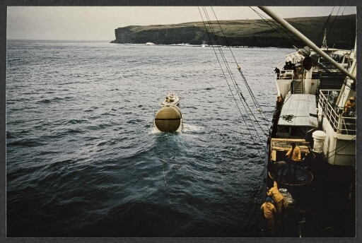 Vue d'une partie d'un navire, une embarcation tire une cuve vers l'île de la Possession.