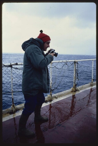 Un homme sur le pont d'un navire tenant un appareil Diapo