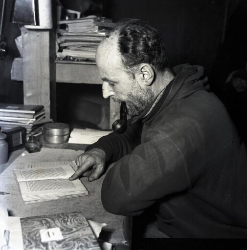 Le chef de mission André Frank Liotard, pipe au bec, lisant à son bureau.