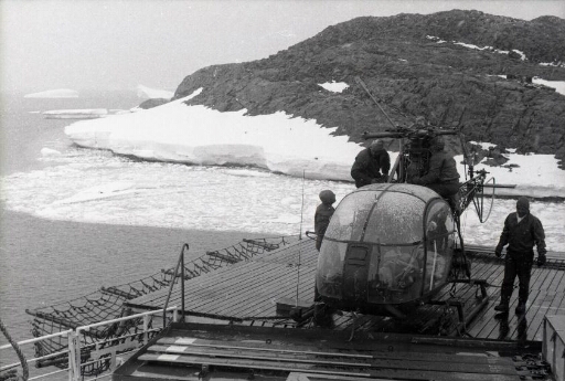 Sur le pont du Thala Dan, sous la neige, quatre membres du détachement "hélico" installent le rotor de leur machine.