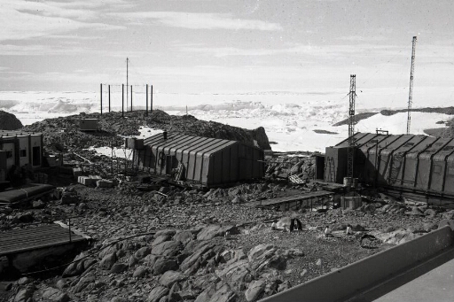 Vue sur l'ancienne base prise du toit du bâtiment séjour. L'antenne caroline et en arrière-plan le glacier de l'Astrolabe.