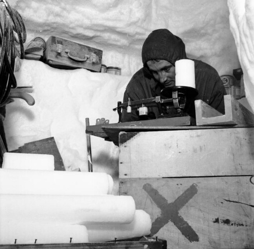 Dans le labo creusé dans la glace, Claude Lorius pèse une carotte de glace prélevée dans le névé.