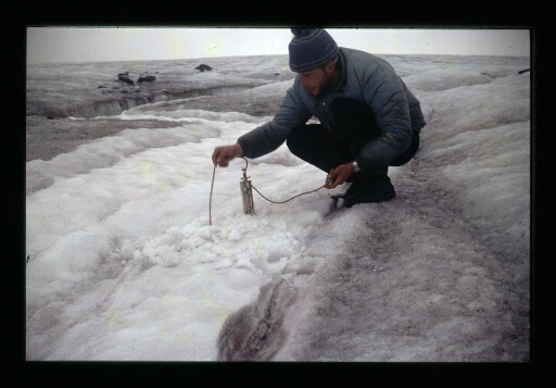 Un homme faisant des mesures sur le sol enneigé- mission CNRS 1966