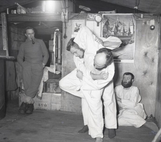 Sport et détente : deux hommes se livrent à un combat de judo sous l'œil de deux de leurs camarades.