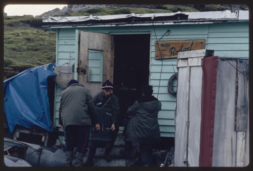 Ile Haute : Trois hommes en ciré devant l'entrée d'une cabane.