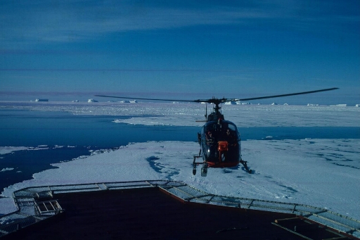 Appontage de l'hélicoptère sur le Thala Dan. Alternance de mer libre et de banquise à perte de vue. Icebergs à l'horizon.