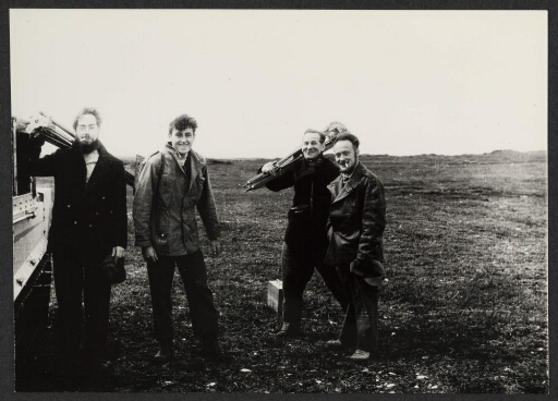 Vers Pointe Guite : Groupe d'hommes souriant vers l'objectif et portant des pieds d'équipements scientifiques
