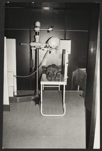 Un homme allongé sur une table sous un appareil de radiologie.