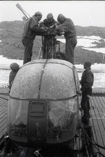 Sur le pont du Thala Dan, sous la neige, cinq membres du détachement "hélico" installent le rotor de leur machine.