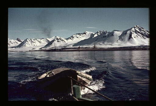 Une barque en bois tirée par un navire au milieux d'un fjord - mission CNRS 1966