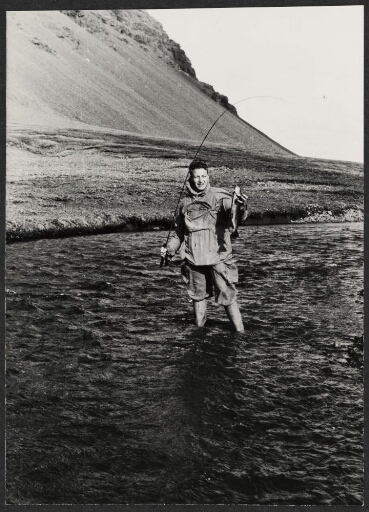 Un homme debout dans l'eau tient une canne à pêche avec son appât.