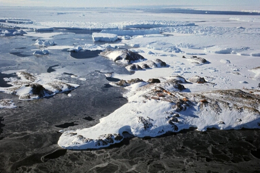 Survol, vers le sud-est, de l'île des pétrels et des îles proches. Glace de mer en formation, quelques icebergs tabulaires.