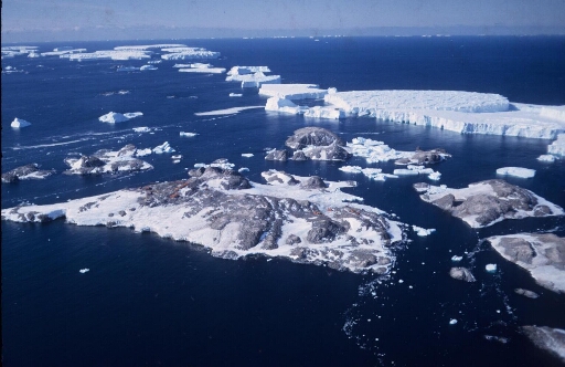 Vue aérienne vers l'est-nord-est de l'archipel en direction du glacier de l'Astrolabe et de ses icebergs. Mer libre à perte de vue.