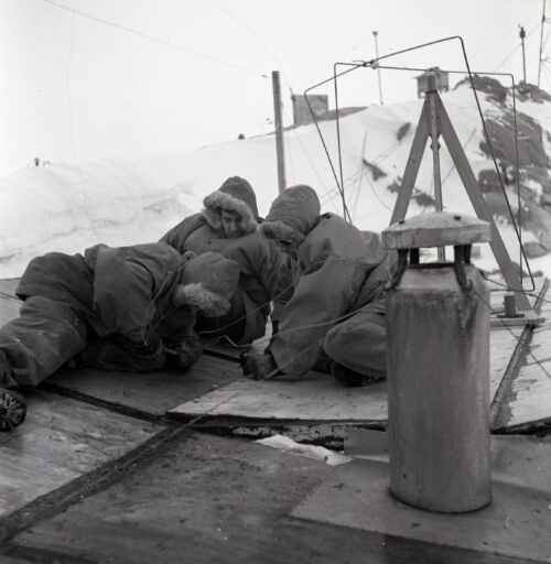 Trois hommes sur le toit de la base effectuent une réparation.