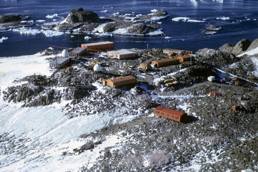 Survol du centre de la base. Les îles Cuvier et du Lion. A gauche, l'abri ballons-sondes incendié en juin 1970. Très beau temps calme.