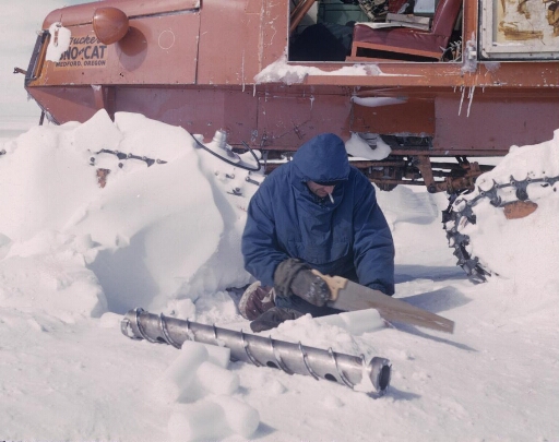 Le glaciologue Claude Lorius découpe une carotte de glace. Au second plan, un Sno-Cat.