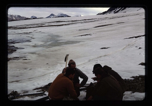 Un groupe d'homme accroupi pour discuter près d'une plaine de neige - mission CNRS 1966